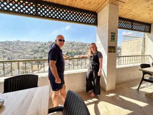 Un uomo e una donna in piedi su un balcone di Villa Mira GuestHouse 2 - Downtown Central Amman - AL DIYRIH ad Amman