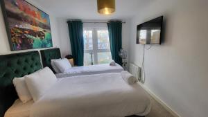 a bedroom with two beds and a tv and a window at Garland Central City Apartment London 2 in London