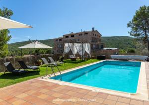 a villa with a swimming pool in front of a building at Masia Aubareda in San Martín de Tous