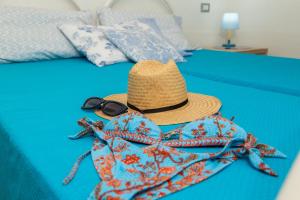 a hat and sunglasses sitting on top of a bed at VILLE MONDO a 350 metri dalla spiaggia in Àrbatax
