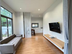 een woonkamer met een bank en een flatscreen-tv bij Villa Taa Koh Samui in Nathon Bay