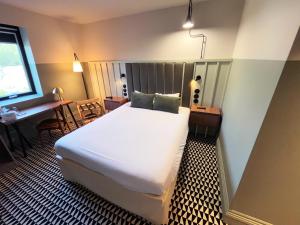 a bedroom with a bed and a desk and a window at Kyriad Compiègne in Compiègne