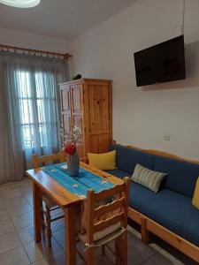 Nikolaos studios apartments في سكوبيلوس تاون: غرفة معيشة مع أريكة زرقاء وطاولة