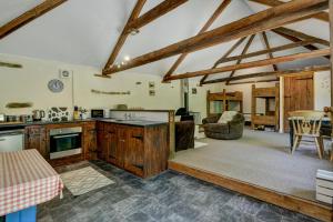 a kitchen with wooden cabinets and a living room at The Cart Shed Brendon Hills in Upton