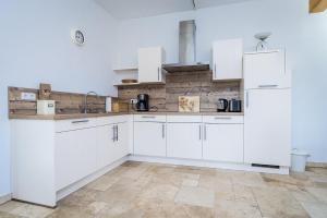 a white kitchen with white cabinets and a tile floor at Hofgut Dösterhof - Ferienwohnungen in Wadern