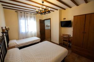 1 Schlafzimmer mit 2 Betten, einem Schreibtisch und einem TV in der Unterkunft POSADA LEPANTO in Socuéllamos
