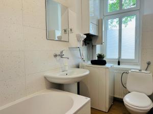a white bathroom with a sink and a toilet at Kwatery Oliwka in Sopot