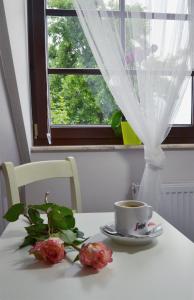 stół z filiżanką kawy i kwiatami w obiekcie Guest House Na Piętrze w Kazimierzu Dolnym