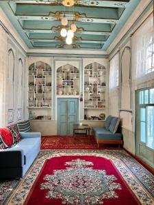 a living room with a blue couch and a red rug at Usman Heritage Hotel in Bukhara