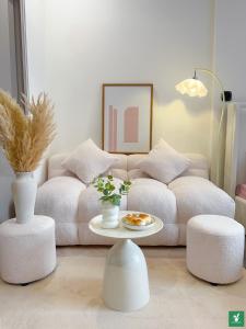 - un salon avec un canapé, une table et deux tabourets dans l'établissement Bunny Bliss-Service Apartment, à Hanoï