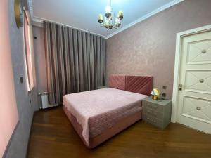 a bedroom with a pink bed and a chandelier at Rezidens CASPIAN LINE in Buzovna