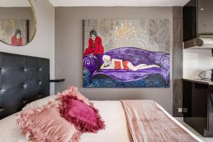 1 dormitorio con 1 cama con una pintura en la pared en PINK port nature coursive naturiste, en Cap d'Agde