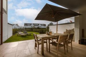 - une table en bois avec un parasol sur la terrasse dans l'établissement Apartment with garden at the seaside in Knokke, à Knokke-Heist