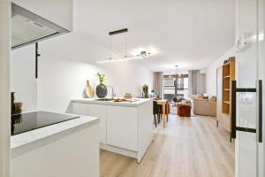 eine Küche mit weißen Schränken und ein Wohnzimmer in der Unterkunft Fully equipped apartment with lateral sea view in Blankenberge