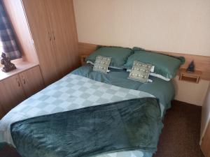 a bedroom with a bed with green sheets and pillows at SANDY BAY STAYOVER in North Seaton