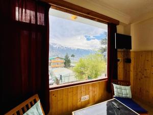 a window in a room with a view of a mountain at The Suraj lodge, Hadimba Road Manali in Manāli