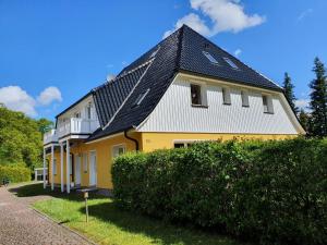 a yellow and white house with a black roof at Ferienwohnung NH14 in Hirschburg