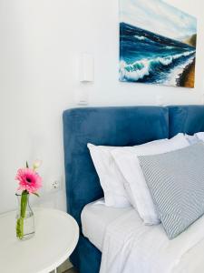 a blue bed with a vase with a pink flower on a table at Villa Fotini in Firostefani