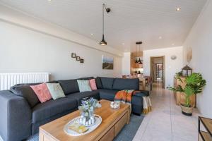 a living room with a blue couch and a table at Huswell - Beachfront apartment in Zeebrugge in Bruges +19 photos