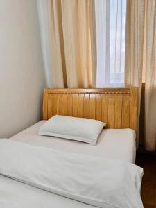 a bed with a wooden headboard next to a window at Khongor Guest house & Tours in Ulaanbaatar