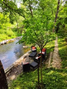 a row of chairs sitting next to a river at Luxury Resort Riverfront with Pool&Sports in Višegrad