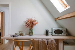 a table with a microwave and a vase with flowers at Charming room in the green neighbourhood of Gent in Ghent