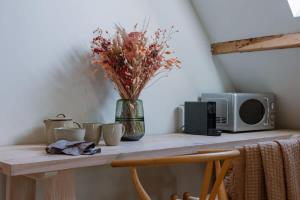 a table with a vase of flowers and a microwave at Charming room in the green neighbourhood of Gent in Ghent