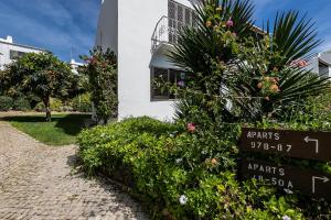 a white building with a sign next to some plants at Apartment in São Rafael Albufeira Beach Resort in Albufeira