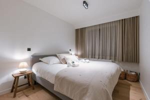 1 dormitorio con 1 cama blanca grande y ventana en High-end apartment in centre of Knokke with parking, en Knokke-Heist