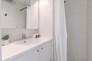La salle de bains blanche est pourvue d'un lavabo et d'une douche. dans l'établissement Cosy studio in Middelkerke, à Middelkerke