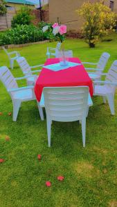a white table and chairs with a red table cloth at DreamWest Living The Guesthouse in Krugersdorp