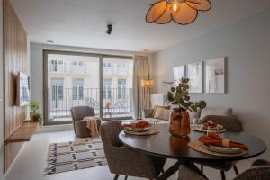 een woonkamer met een tafel en stoelen en een woonkamer bij City at Sea - Modern 1 bedroom apartement in Oostende
