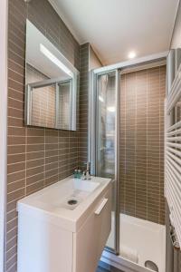 een badkamer met een witte wastafel en een douche bij Cosy apartment with ocean view in Knokke-Heist