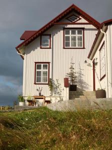 Una casa blanca con un árbol delante. en Hótel Karólína, en Stykkishólmur