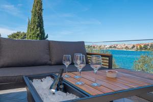a wooden table with wine glasses on a couch at Holiday Home Family Fun in Grebaštica