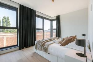 a white bedroom with a bed and large windows at Spacious apartment with beautiful terrace near Ghent in Ghent
