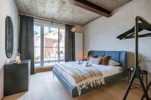 sypialnia z niebieskim łóżkiem i dużym oknem w obiekcie Industrial apartment with terrace in Antwerp w Antwerpii