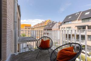 een balkon met 2 stoelen en uitzicht op de gebouwen bij Modern apartment with sunny terrace in Ostend in Oostende