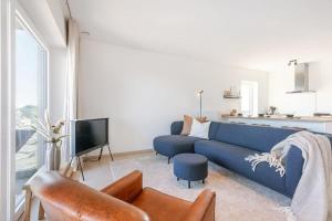 ein Wohnzimmer mit einem blauen Sofa und einem TV in der Unterkunft Brand new apartment with stunning harbor views in Brügge