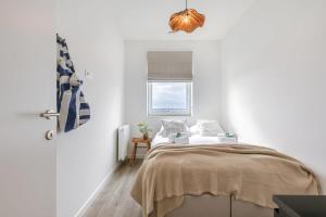 a white bedroom with a bed and a window at Brand new apartment with stunning harbor views in Bruges