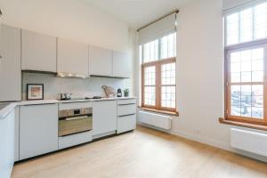 eine leere Küche mit weißen Schränken und Fenstern in der Unterkunft Huswell - Modern apartment located at historical Main Square in Antwerpen
