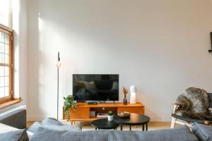 ein Wohnzimmer mit Sofa und Fernseher in der Unterkunft Huswell - Modern apartment located at historical Main Square in Antwerpen