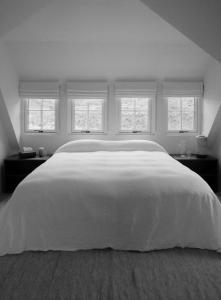 a bedroom with a large white bed with windows at Laggan Cottage - Charming home along River Gairn in Ballater