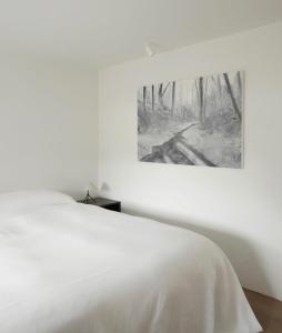 Un dormitorio con una cama blanca con una foto en la pared en Laggan Cottage - Charming home along River Gairn, en Ballater