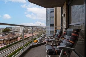 einen Balkon mit Stühlen in einem Gebäude mit Bahngleis in der Unterkunft Spacious apartment with lateral sea view in Blankenberge