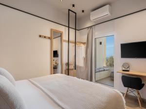 a bedroom with a bed and a desk and a television at Alexia Beach Hotel in Agia Marina Nea Kydonias