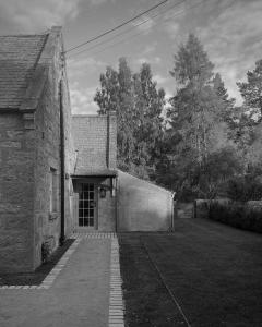 an old stone building with a door in a yard at Oldschool - Exclusive house surrounded by a dyke in Ballater