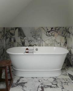 a white bath tub in a bathroom with marble walls at Oldschool - Exclusive house surrounded by a dyke in Ballater