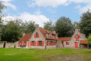 亞貝克的住宿－Authentic Villa 'Amore' located in nature near Bruges，一座古老的石头房子,在田野上设有红色窗户