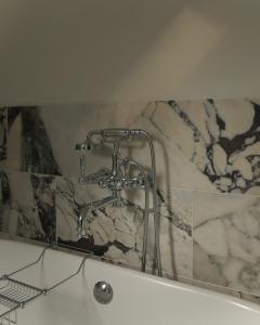 a bath tub with a shower faucet in a bathroom at Oldschool - Exclusive house surrounded by a dyke in Ballater